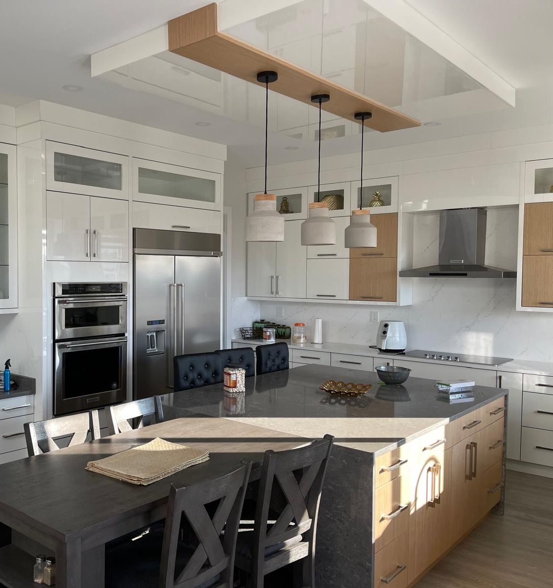 Gloss white kitchen with an oak-veneer island and glass display hutch