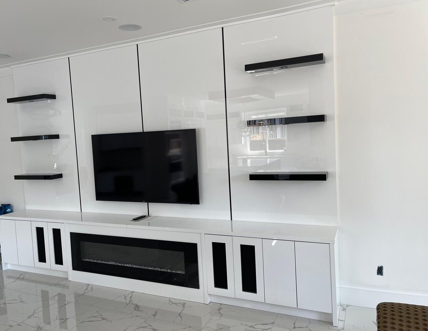 Gloss white media wall with black floating shelves and speaker doors